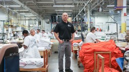 Man standing between working inmates at sewing shop