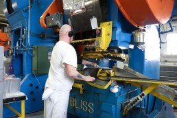 inmate operating large press machine to engrave license plates