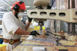 Inmate drilling holes in metal sheet using large drill machine