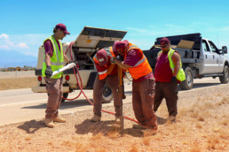 External work crew inmates installing marker posts on side of road